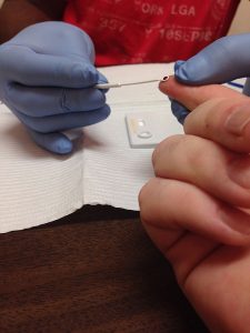 Person pricking a finger for rapid HIV testing