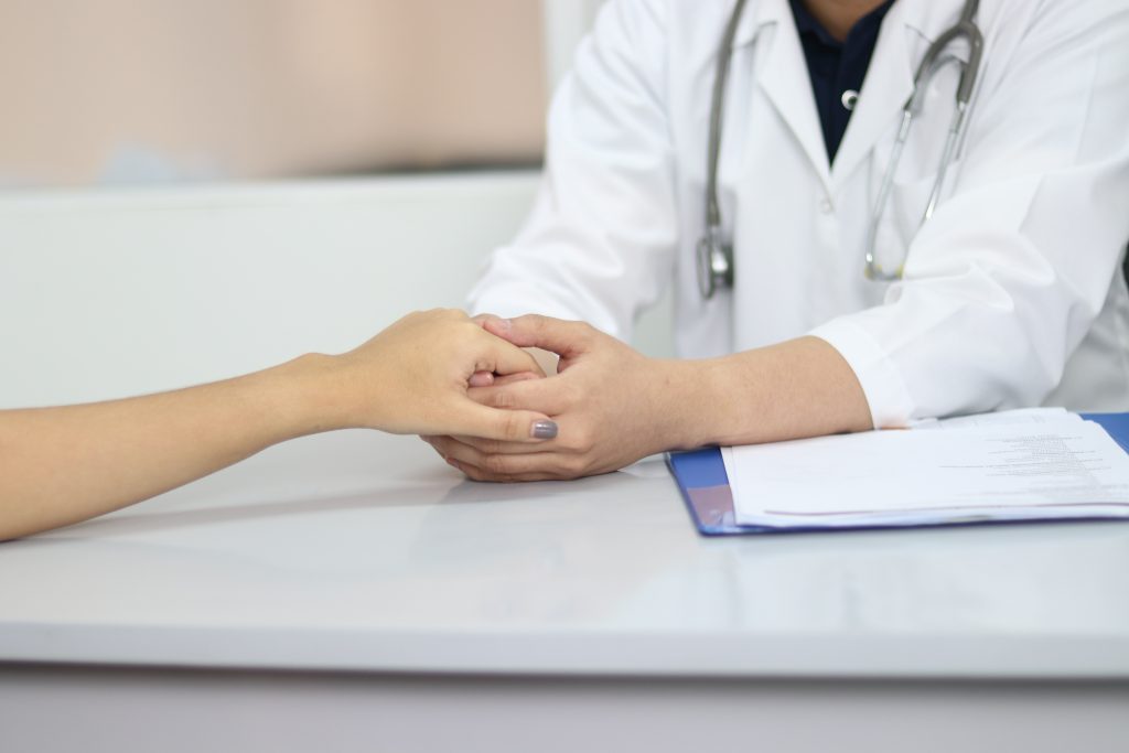 A doctor holds a patient's hand