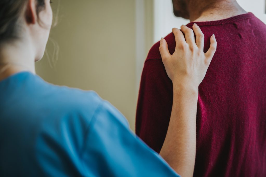 A woman in blue places her hand on a man's shoulder after he uses the STD symptom checker